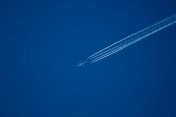 jet plane high in the blue sky with a contrail