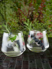 Gin tonic decorated with a rosemary sprig and fresh berries