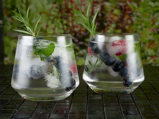 Gin tonic decorated with a rosemary sprig and fresh berries