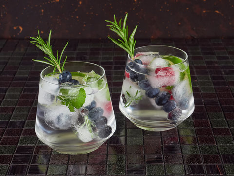 Gin tonic decorated with a rosemary sprig and fresh berries