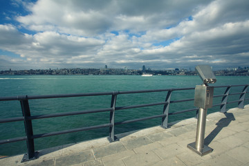 Travel concept. Tourist coin binocular at quay for promenade in Uskudar, the Bosphorus, Istanbul, Turkey. Sunny day. Blue cloudy sky. View to Galata Tower. Outdoor shot