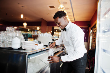 African american bartender at bar picks up ice. Alcoholic beverage preparation.