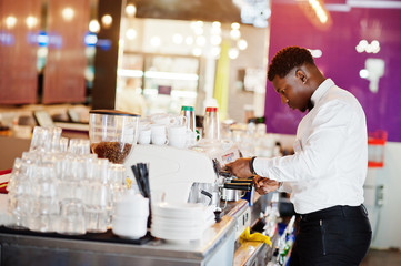 African american bartender barista at bar preparing coffee.