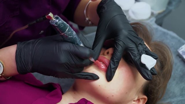 Permanent make up. Cosmetologist applying permanent makeup on lips