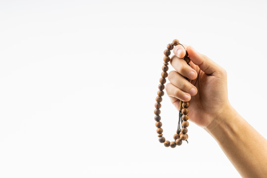 Hand holding a muslim rosary beads or Tasbih on white background. Copy space and selective focus