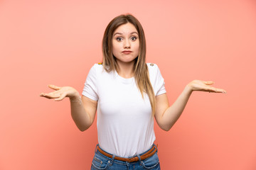 Teenager girl over isolated pink wall having doubts with confuse face expression