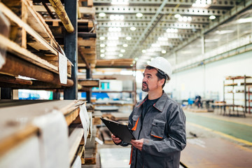 Man in protective work wear working at heavy industry warehouse.