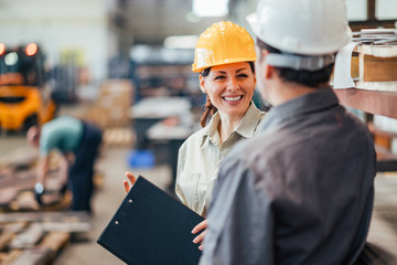 Coworkers talking and smiling at heavy industry factory, close-up.