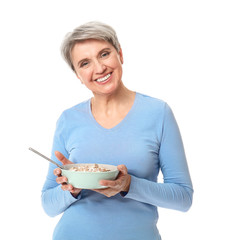 Mature woman with bowl of oatmeal on white background