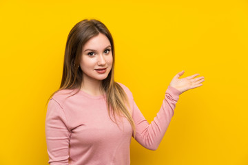 Teenager girl over isolated yellow background holding copyspace imaginary on the palm