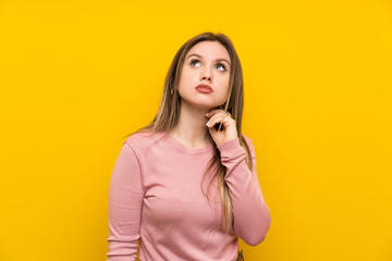 Teenager girl over isolated yellow background thinking an idea