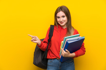 Teenager student girl over yellow background pointing finger to the side
