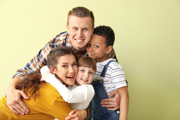 Fototapeta premium Happy couple with little adopted children on color background