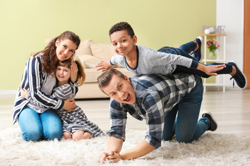 Happy couple playing with little adopted children at home