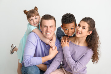 Happy couple with little adopted children on white background