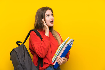 Teenager student girl over yellow background shouting with mouth wide open