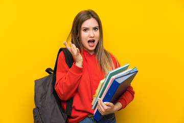 Teenager student girl over yellow background unhappy and frustrated with something