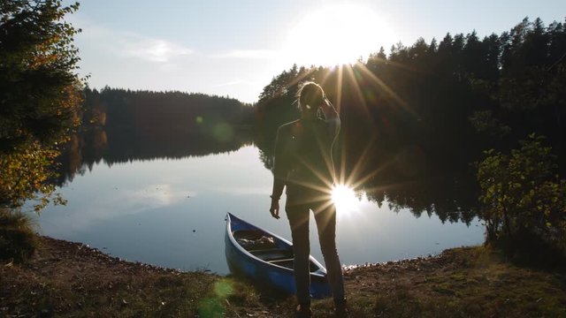 Girl hiker looking sunset view over lake before going canoeing