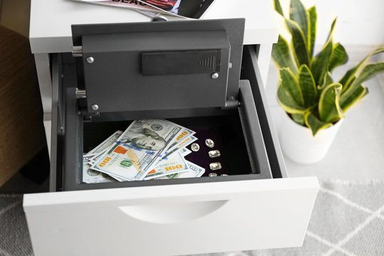 Small modern safe with money in cabinet drawer