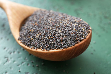Spoon with poppy seeds on table, closeup