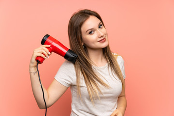 Teenager girl over pink background with hair dryer
