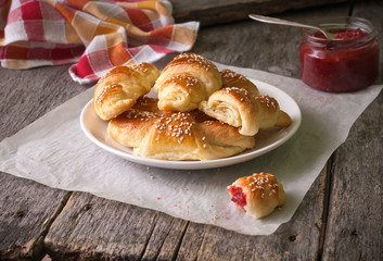 Homemade croissants with berry jam on wooden background