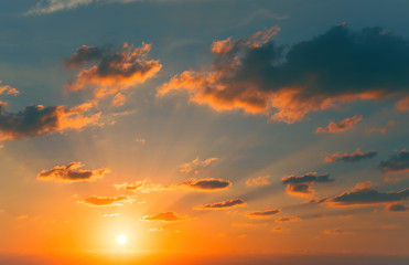 Beautiful view of a sunset sky with sun, sunrays and clouds. Nature summer background.