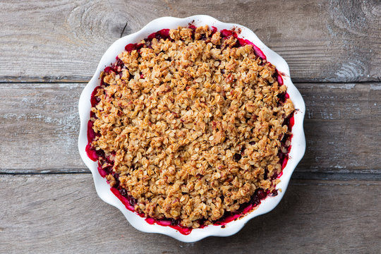 Berry crumble, crisp in baking dish. Wooden background. Top view.