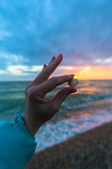 shell in the hand of the girl against the sea and sunset