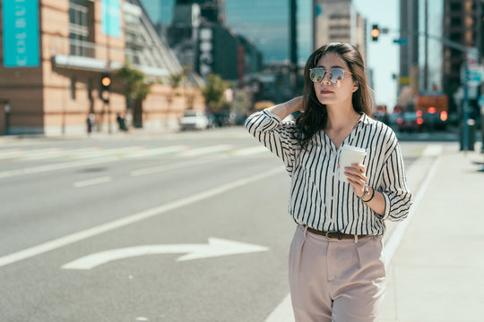 Young Urban Casual Business Woman Happy In New York City Manhattan Drinking Coffee Walking In Street Downtown Waiting For Yellow Taxi Cabs In Background. Office Lady Hold Take Away Cup On Road.