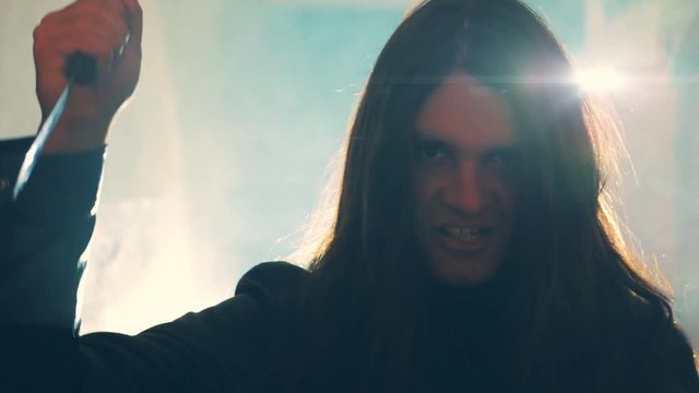 Maniac or killer or horror murderer with knife in hand in dark creepy and spooky corridor with back light. Criminal robber or rapist concept in thriller atmosphere