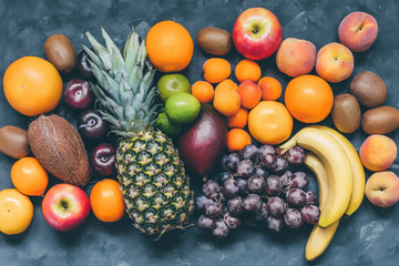 Assortment of fruit pineapple,pitaya,bananas, mango,  grapes, orange, apple, coconut, peaches, apricots, tangerines, lemon and kiwi top view