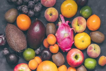 Assortment of fruit pineapple,pitaya,bananas, mango,  grapes, orange, apple, coconut, peaches, apricots, tangerines, lemon and kiwi top view