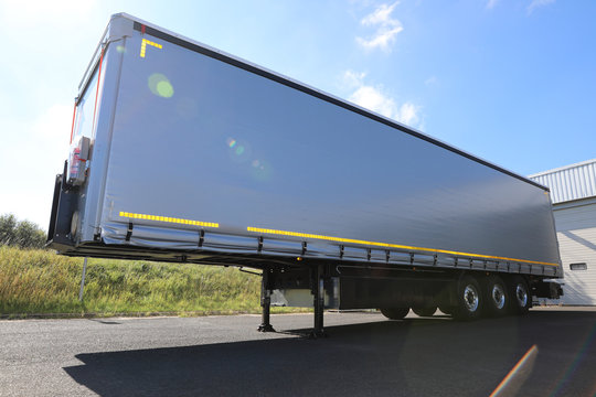 Semi remorque gris triple essieux. Mat&eacute;riel de transport, remorques europe. Semi remorque europ&eacute;en stationn&eacute; proche d'un d&eacute;p&ocirc;t de marchandises.