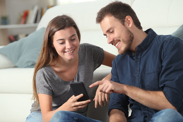 Happy couple checking smart phone apps at home