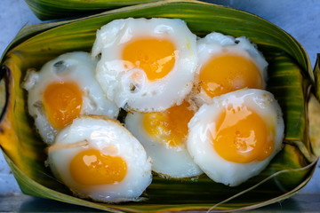 Fried quail egg In the container made of banana leaves is a street food in local market in Thailand, closeup. Thai food