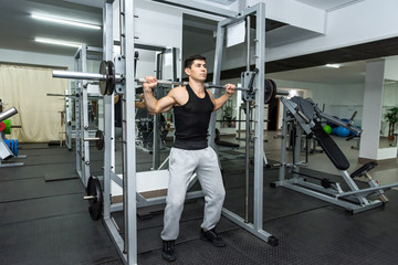 Fototapeta na wymiar Young man lifting up barbell in gym