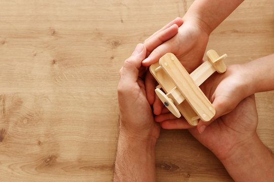 photo of father and little child holding together wooden toy plane. Happy father's day and holiday concept. top view, above