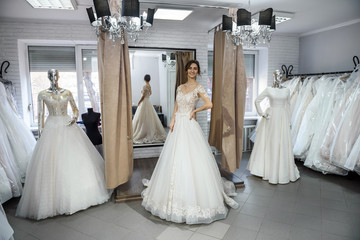 Young and tiny bride in wedding dress in salon