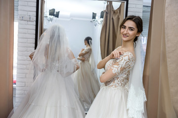 Naklejka premium Happy bride in salon posing in wedding dress