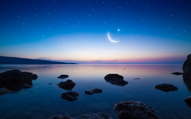 Ramadan Kareem background with crescent and stars above serene sea