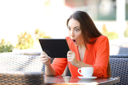 Shocked woman watching and listening media on tablet