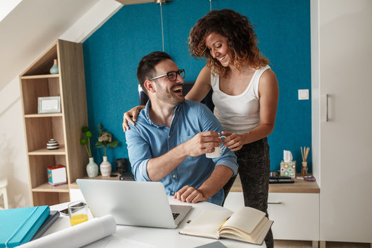 Mid age businessman working at home.Wife stands beside and support him.