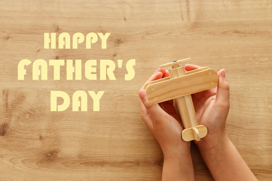 photo of little child holding wooden toy plane. Happy father's day and holiday concept. top view, above