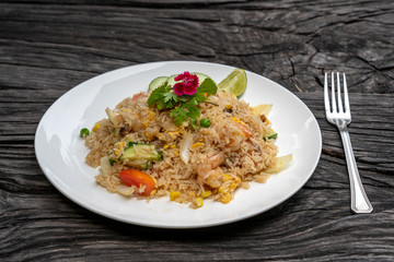 Fried rice with shrimps and vegetables in a white dish on an old wooden table, close up . Thai food , Thai cuisine