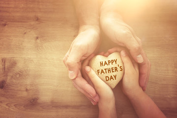 father and little child holding together wooden heart. Happy father's day concept.