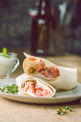 Fresh tortilla wrap with vegetables and salmon on plate