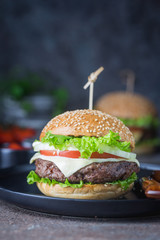 Hamburger with beef meat burger and fresh vegetables on dark background. Tasty fast food.