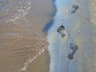 Footprints on sandy lake beach and waves 