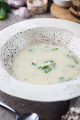 Fresh asparagus cream soup in a bowl over gray stone table